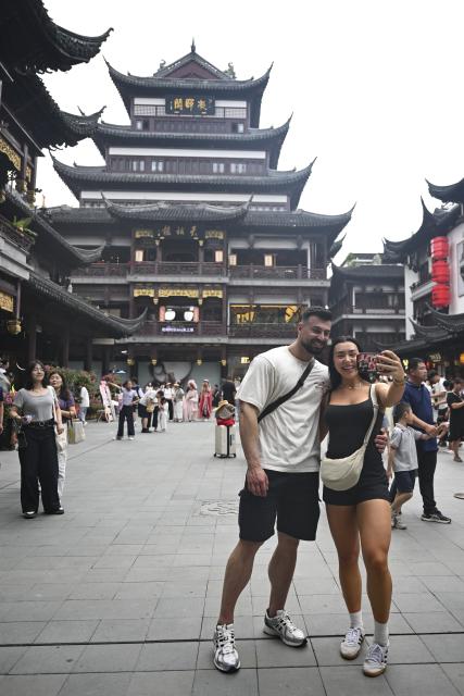 (251004) -- SHANGHAI, Oct. 4, 2025 (Xinhua) -- Australian tourists Gio Valentino (L) and Christina Karropoulos take selfies at Yuyuan Garden Mall in east China's Shanghai, Oct. 3, 2025. The eastern Chinese megacity of Shanghai received a whopping 4.1 million overseas visitors from January to August this year.
  The latest tourism boom in the city has resulted from a series of policies that provide greater convenience for international tourists entering China. As one of the country's most famous tourist cities, Shanghai is usually among the first places affected by new policies for the sector.
    According to Shanghai General Station of Immigration Inspection, the airport ports in Shanghai are expected to handle 883,000 inbound and outbound passengers during the National Day holiday from Oct. 1 to 8, which is a daily average of 116,000 passengers, a 22.3 percent increase year on year. (Xinhua/Chen Haoming)
