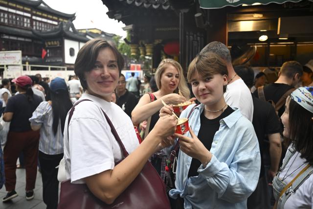 (251004) -- SHANGHAI, Oct. 4, 2025 (Xinhua) -- Tourists from Russia taste snacks at Yuyuan Garden Mall in east China's Shanghai, Oct. 3, 2025. The eastern Chinese megacity of Shanghai received a whopping 4.1 million overseas visitors from January to August this year.
  The latest tourism boom in the city has resulted from a series of policies that provide greater convenience for international tourists entering China. As one of the country's most famous tourist cities, Shanghai is usually among the first places affected by new policies for the sector.
    According to Shanghai General Station of Immigration Inspection, the airport ports in Shanghai are expected to handle 883,000 inbound and outbound passengers during the National Day holiday from Oct. 1 to 8, which is a daily average of 116,000 passengers, a 22.3 percent increase year on year. (Xinhua/Chen Haoming)