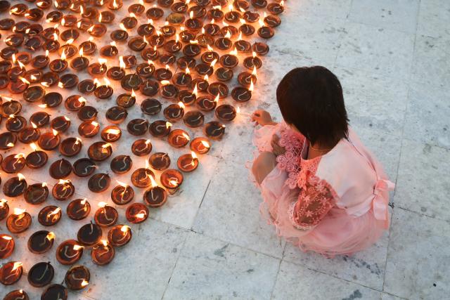 (251006) -- YANGON, Oct. 6, 2025 (Xinhua) -- A girl lights candles on the full moon day of Thadingyut festival at the Botataung Pagoda in Yangon, Myanmar, Oct. 6, 2025. (Xinhua/Myo Kyaw Soe)