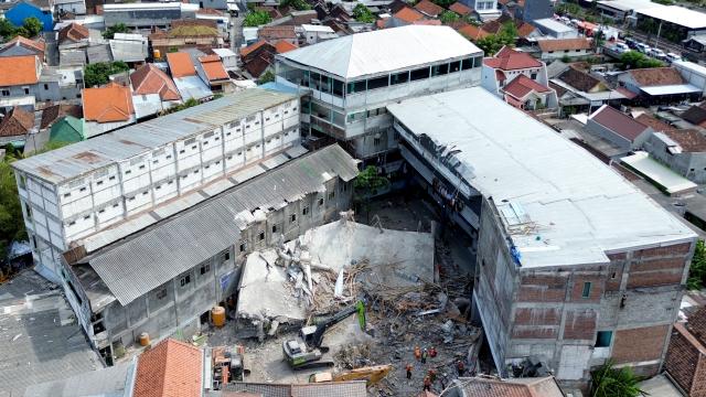 (251006) -- SIDOARJO, Oct. 6, 2025 (Xinhua) -- An aerial drone photo taken on Oct. 5, 2025 shows rescuers working with an excavator at the site of a collapsed school building in Sidoarjo district, East Java, Indonesia. The death toll from the collapse of a building of the Al Khoziny Islamic boarding school in Sidoarjo Regency, East Java, has risen to 60 after search and rescue teams recovered 11 more bodies on Monday, according to Indonesia's National Disaster Management Agency (BNPB) (Photo by Sahlan Kurniawan/Xinhua)
