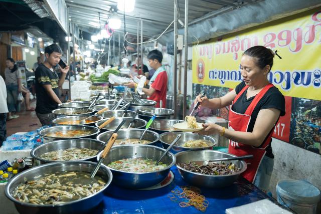 (251012) --LUANG PRABANG, Oct. 12, 2025 (Xinhua) -- A woman prepares food at a booth in Luang Prabang, Laos, Oct. 10, 2025. According to the World Bank statistics, the female population in Laos accounted for 49.8 percent of the country's total population in 2024. (Photo by Kaikeo Saiyasane/Xinhua)