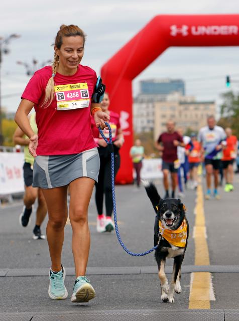 (251013) -- BUCHAREST, Oct. 13, 2025 (Xinhua) -- A participant runs with her dog during the Bucharest Marathon in Bucharest, Romania, Oct. 12, 2025. (Photo by Cristian Cristel/Xinhua)