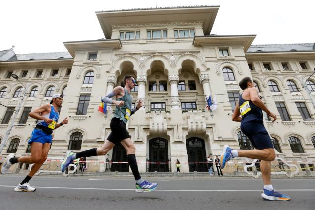 (251013) -- BUCHAREST, Oct. 13, 2025 (Xinhua) -- Participants run past Bucharest's townhall during the Bucharest Marathon in Bucharest, Romania, Oct. 12, 2025. (Photo by Cristian Cristel/Xinhua)