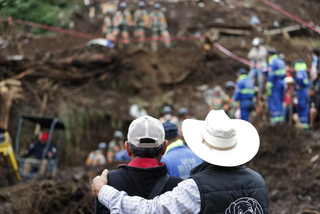 (251013) -- HUAUCHINANGO(MEXICO), Oct. 13, 2025 (Xinhua) -- This photo taken on Oct. 13, 2025 shows people watching search and rescue operation at a landslide site caused by the heavy rain in Huauchinango, Puebla state, Mexico. At least 64 people have died and dozens remain missing after days of torrential rains and flooding that hit central and eastern Mexico last week, authorities said Monday. (Photo by Francisco Canedo/Xinhua)