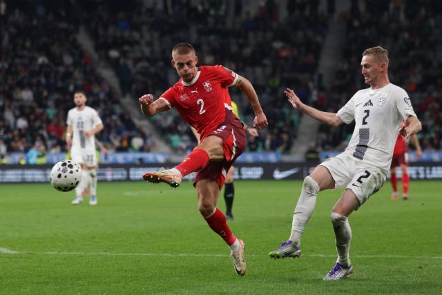 (251014) -- LJUBLJANA, Oct. 14, 2025 (Xinhua) -- Miro Muheim (L) of Switzerland shoots during the World Cup 2026 European Qualifiers Group B football match between Slovenia and Switzerland in Ljubljana, Slovenia, Oct. 13, 2025. (Photo by Zeljko Stevanic/Xinhua)