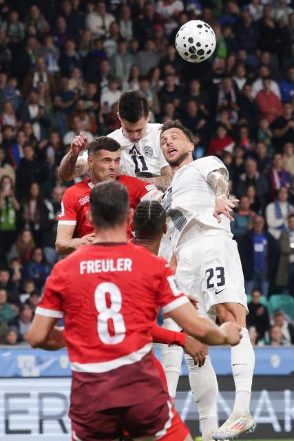 (251014) -- LJUBLJANA, Oct. 14, 2025 (Xinhua) -- Benjamin Sesko (top) and David Brekalo (R) of Slovenia compete for a header with Granit Xhaka (L) of Switzerland during the World Cup 2026 European Qualifiers Group B football match between Slovenia and Switzerland in Ljubljana, Slovenia, Oct. 13, 2025. (Photo by Zeljko Stevanic/Xinhua)