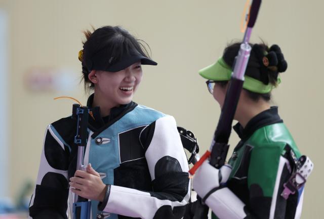 (251014) -- BEIJING, Oct. 14, 2025 (Xinhua) -- Silver medalist Yan Jinjing (L) of Jiangsu talks with gold medalist Han Jiayu of Zhejiang after the 10m air rifle women's final of shooting at China's 15th National Games in Guangzhou, south China's Guangdong Province, Oct. 13, 2025. (Xinhua/Lu Hanxin)