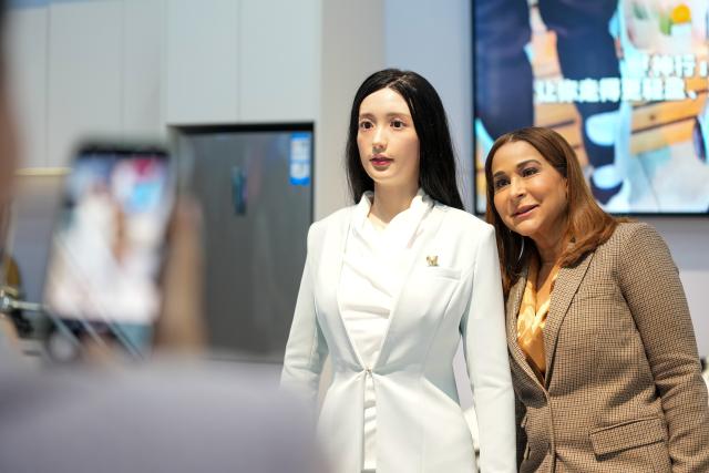 (251014) -- BEIJING, Oct. 14, 2025 (Xinhua) -- A representative, who is in Beijing for the Global Leaders' Meeting on Women, poses for photos with a humanoid robot at the Beijing World of Robots in Beijing, capital of China, Oct. 14, 2025. (Xinhua/Xue Yuge)