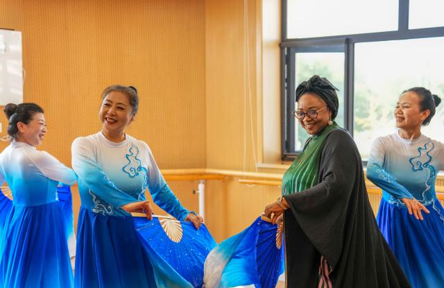 (251014) -- BEIJING, Oct. 14, 2025 (Xinhua) -- A representative, who is in Beijing for the Global Leaders' Meeting on Women, dances with dancing enthusiasts at a social service center for women and children in Shunyi District in Beijing, capital of China, Oct. 14, 2025. (Xinhua/Yan Linyun)