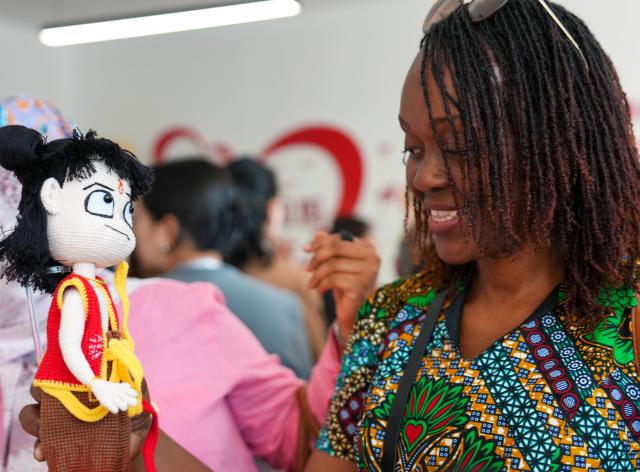 (251014) -- BEIJING, Oct. 14, 2025 (Xinhua) -- A representative, who is in Beijing for the Global Leaders' Meeting on Women, looks at a handmade toy in the shape of Nezha (a popular figure in Chinese myth) at a social service center for women and children in Shunyi District in Beijing, capital of China, Oct. 14, 2025. (Xinhua/Yan Linyun)