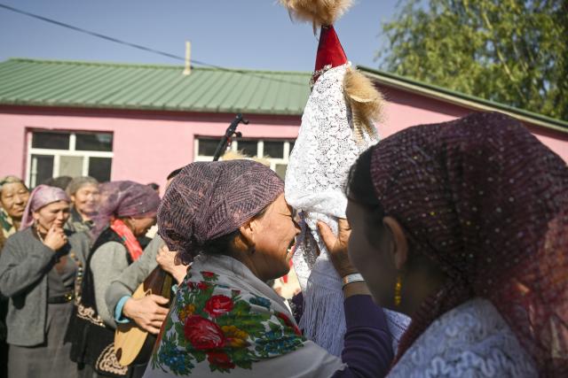 (251014) -- TEKES, Oct. 14, 2025 (Xinhua) -- A relative of the groom Bukehan Yelszi expresses blessings to the bride Kumusi Yesdawulti in Karadala Township of Tekes County, northwest China's Xinjiang Uygur Autonomous Region, Oct. 11, 2025.
  A blue sky, white clouds, vast grassland, horses and automobiles set a poetic and picturesque wedding scene for the newlyweds Kumusi Yesdawulti and Bukehan Yelszi. 
  For the couple, having fallen in love a year ago, a traditional wedding ceremony was at the top of their to-do list.
  Without a hair out of place, Kumusi, dressed head to toe in traditional costume and adorned in a red veil, married her better half Bukehan, describing the wedding as a dream realized.
  Throughout the wedding festivities, the couple's loved ones congregated to join in the celebration. Some of them played traditional musical instruments, such as dombra, and performed inspiring festive dances, while others lent their hands to prepare local specialties, including naan bread and baursak.
  A modern outdoor wedding ensued at dusk in a forest park, where the couple shared champagne and danced with their relatives and friends. The event's long-lasting atmosphere of joy, harmony and warmth drew locals and tourists to immerse themselves in joy and happiness together.
  "With horses and automobiles, the wedding is really special and lively," said Kumusi. (Xinhua/Hu Huhu)