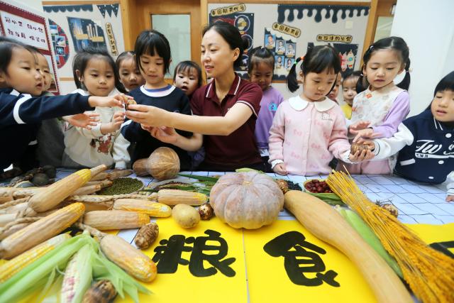 (251014) -- BEIJING, Oct. 14, 2025 (Xinhua) -- Children learn to identify grains under the guidance of a teacher at a kindergarten in Lianyungang City, east China's Jiangsu Province, on Oct. 14, 2025. Theme events have been carried out across China to mark World Food Day that falls on Oct. 16. (Photo by Wang Chun/Xinhua)