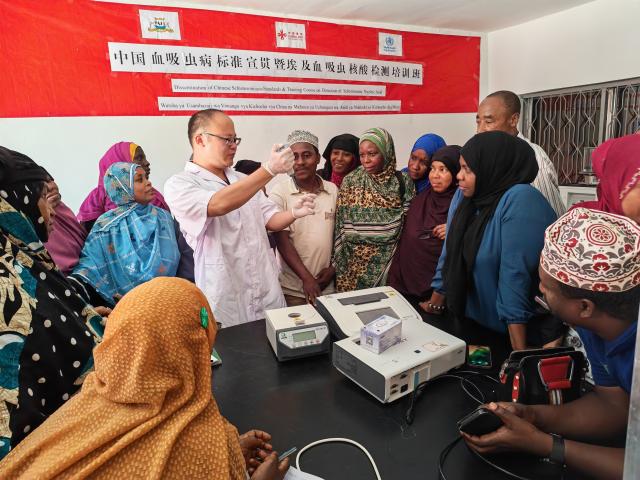 (251015) -- ZANZIBAR, Oct. 15, 2025 (Xinhua) -- A Chinese health expert demonstrates diagnostic techniques for schistosomiasis to Zanzibari health professionals during a training workshop in Zanzibar, Tanzania, Oct. 14, 2025. TO GO WITH "Chinese standards strengthen schistosomiasis elimination efforts in Tanzania's Zanzibar" (Chinese expert team/Handout via Xinhua)
