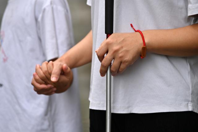 (251015) -- FENGSHAN, Oct. 15, 2025 (Xinhua) -- Lan Yezhen (R) and her younger son take a walk together in a residential area in Fengshan County, south China's Guangxi Zhuang Autonomous Region, Oct. 14, 2025.
  Lan Yezhen, a visually impaired writer from rural Guangxi, has carved a path of resilience through words.
   Life took a harsh turn when she had to forgo the national college entrance examination after her mother's passing. She then spent years working as a migrant worker.
   In 2018, progressive eye conditions left her completely blind, plunging the mother of two young children into despair.
   Amid the darkness, audiobooks became her beacon of solace. Inspired by literary characters who overcame adversity, she began documenting her own life story.
   With growing support from her community and beyond, Lan persisted in her writing. Her essays were published in literary journals, which led to her admission into the Guangxi Writers Association in 2024.
   Through her words, she invites readers into her inner world and reveals the hope that endures despite adversity.
   "Writing helped me find my own light," Lan said. "Even in darkness, I can carve out a path forward for myself." (Xinhua/Lu Boan)