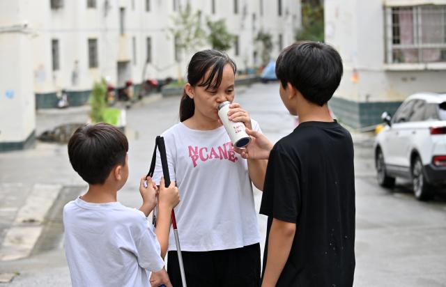(251015) -- FENGSHAN, Oct. 15, 2025 (Xinhua) -- Lan Yezhen drinks water while walking in a residential area with her sons in Fengshan County, south China's Guangxi Zhuang Autonomous Region, Oct. 14, 2025.
  Lan Yezhen, a visually impaired writer from rural Guangxi, has carved a path of resilience through words.
   Life took a harsh turn when she had to forgo the national college entrance examination after her mother's passing. She then spent years working as a migrant worker.
   In 2018, progressive eye conditions left her completely blind, plunging the mother of two young children into despair.
   Amid the darkness, audiobooks became her beacon of solace. Inspired by literary characters who overcame adversity, she began documenting her own life story.
   With growing support from her community and beyond, Lan persisted in her writing. Her essays were published in literary journals, which led to her admission into the Guangxi Writers Association in 2024.
   Through her words, she invites readers into her inner world and reveals the hope that endures despite adversity.
   "Writing helped me find my own light," Lan said. "Even in darkness, I can carve out a path forward for myself." (Xinhua/Lu Boan)