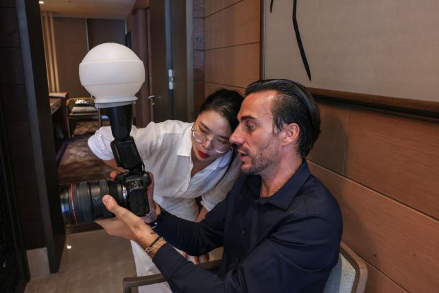 (251015) -- HAIKOU, Oct. 15, 2025 (Xinhua) -- French photographer Ludovic Eric Shen (R) communicates with a colleague at a hotel in Lingshui, south China's Hainan Province, Sept. 22, 2025. TO GO WITH "Across China: French lens captures tropical romance, development in south China" (Xinhua/Zhang Liyun)