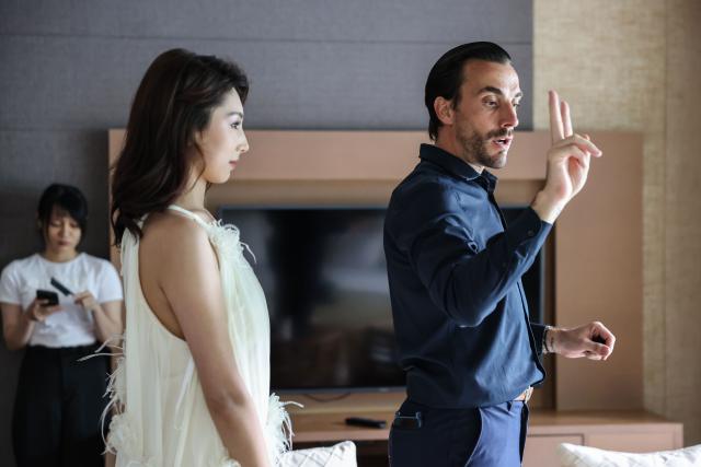 (251015) -- HAIKOU, Oct. 15, 2025 (Xinhua) -- French photographer Ludovic Eric Shen (R) demonstrates a pose for his client at a hotel in Lingshui, south China's Hainan Province, Sept. 22, 2025. TO GO WITH "Across China: French lens captures tropical romance, development in south China" (Xinhua/Zhang Liyun)