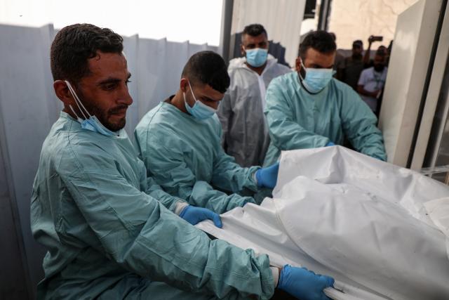 (251015) -- GAZA, Oct. 15, 2025 (Xinhua) -- Medics are seen during the examination of the bodies of Palestinians handed over from Israel to the International Committee of the Red Cross (ICRC), at Nasser Hospital in the southern Gaza Strip city of Khan Younis, Oct. 15, 2025. (Photo by Rizek Abdeljawad/Xinhua)