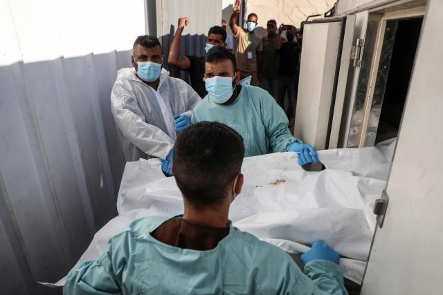 (251015) -- GAZA, Oct. 15, 2025 (Xinhua) -- Medics are seen during the examination of the bodies of Palestinians handed over from Israel to the International Committee of the Red Cross (ICRC), at Nasser Hospital in the southern Gaza Strip city of Khan Younis, Oct. 15, 2025. (Photo by Rizek Abdeljawad/Xinhua)