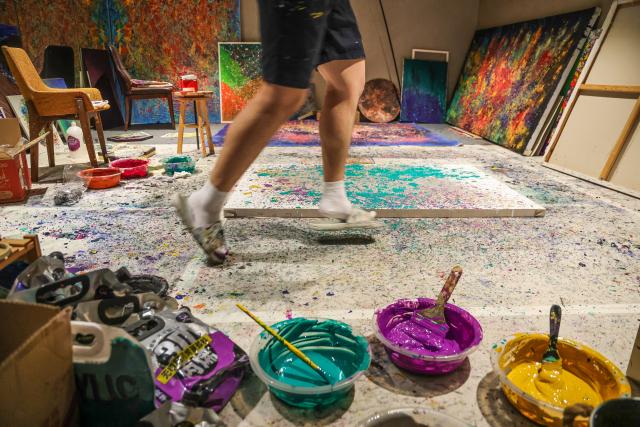 (251016) -- BEIJING, Oct. 16, 2025 (Xinhua) -- Wang Jianshu jumps for joy while creating a drip painting at his studio in Beijing, capital of China, Aug. 8, 2025. Twenty-one years ago, Wang Jianshu's parents welcomed his birth with great hope. At three, he began to show differences from other children, and by five, he was diagnosed with autism.
   To heal him, his parents had chosen various activities for him. In art class, Wang Jianshu showed a special sensitivity to color. His bold and unexpected color combinations came together in strikingly harmonious and imaginative ways. Noticing this talent, his teacher suggested his mother nurture his artistic ability. 
   At first, Wang's mother saw painting merely as a way to help Wang pass the time. But gradually, she noticed he could paint intently for hours, sometimes so joyfully that he would dance and sing while creating. His works also became a bridge for communication within the family. 
   When Wang was twelve, his mother entered his work into a competition. After unexpectedly winning an award, Wang was too excited to sleep that night. Since then, his mother has supported him in participating in exhibitions and publishing painting albums, through which he opened wider to the world.
   Today, Wang Jianshu has created around 2,000 works, many of which have been displayed in exhibitions overseas. He has painted an extraordinary life on the canvas in his own unique way. (Xinhua/Lu Ye)