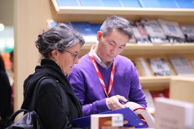 (251016) -- FRANKFURT, Oct. 16, 2025 (Xinhua) -- A woman talks with a staff member of the Reading China booth at the Frankfurt Book Fair in Frankfurt, Germany, Oct. 16, 2025. The world's largest book fair, the Frankfurt Book Fair, opened here on Tuesday with a focus on licensing and rights exchange.
   More than 4,000 publishers from over 90 countries and regions are present at the 77th book fair and more than 200,000 visitors are expected, said Juergen Boos, director of the Fair, at the opening ceremony.
   Chinese publishers are making a strong presence at the book fair, showcasing more than 5,000 titles and 6,500 copies, with foreign-language editions accounting for over one-third of the total. (Xinhua/Du Zheyu)