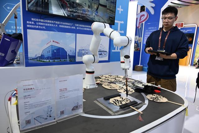 (251016) -- QINGDAO, Oct. 16, 2025 (Xinhua) -- An exhibitor operates a calligraphy robot at the tenth China International Copyright Expo in Qingdao, east China's Shandong Province, Oct. 16, 2025. Themed "Digital Intelligence Leads the Future, Copyright Promotes Innovative Development," the tenth China International Copyright Expo and 2025 International Copyright Forum opened Thursday in Qingdao. (Xinhua/Li Ziheng)