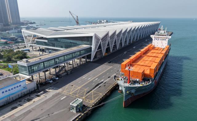 (251016) -- QINGDAO, Oct. 16, 2025 (Xinhua) -- A drone photo taken on Oct. 16, 2025 shows the "SMC RIZHAO" ship performing the maiden voyage of the Qingdao-Jeju container shipping route berthing at the Qingdao International Cruise Terminal in Qingdao, east China's Shandong Province. A regular direct container shipping route between Qingdao and South Korea's Jeju was launched on Thursday. This express shipping route will operate once a week in its initial stage, significantly enhancing the logistics efficiency between the two places, effectively reducing logistics costs, and further densifying the shipping network of east China's Shandong Province to South Korea. (Xinhua/Li Ziheng)