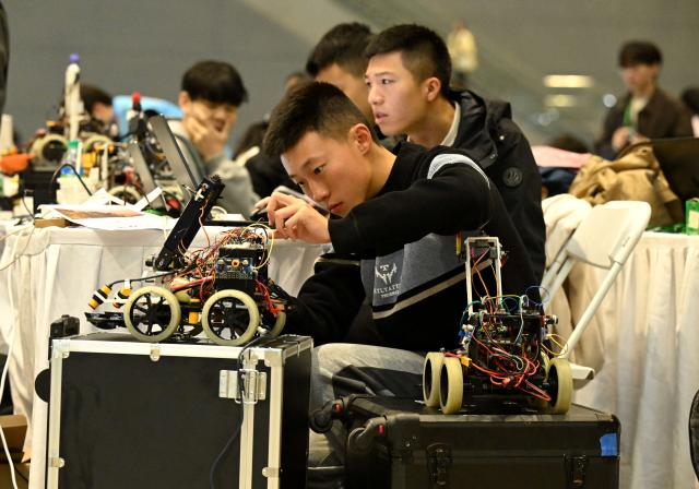 (251017) -- SHIJIAZHUANG, Oct. 17, 2025 (Xinhua) -- A contestant debugs a robot before a game at the International Convention and Exhibition Center in Shijiazhuang, north China's Hebei Province, Oct. 17, 2025. The 2025 China Robot Competition and RoboCup China Open are held here from Friday to Sunday. (Photo by Chen Qibao/Xinhua)