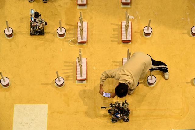 (251017) -- SHIJIAZHUANG, Oct. 17, 2025 (Xinhua) -- A contestant debugs a robot before a game at the International Convention and Exhibition Center in Shijiazhuang, north China's Hebei Province, Oct. 17, 2025. The 2025 China Robot Competition and RoboCup China Open are held here from Friday to Sunday. (Photo by Chen Qibao/Xinhua)