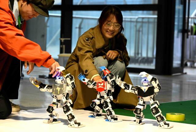 (251017) -- SHIJIAZHUANG, Oct. 17, 2025 (Xinhua) -- Contestants debug robots before a game at the International Convention and Exhibition Center in Shijiazhuang, north China's Hebei Province, Oct. 17, 2025. The 2025 China Robot Competition and RoboCup China Open are held here from Friday to Sunday. (Photo by Chen Qibao/Xinhua)