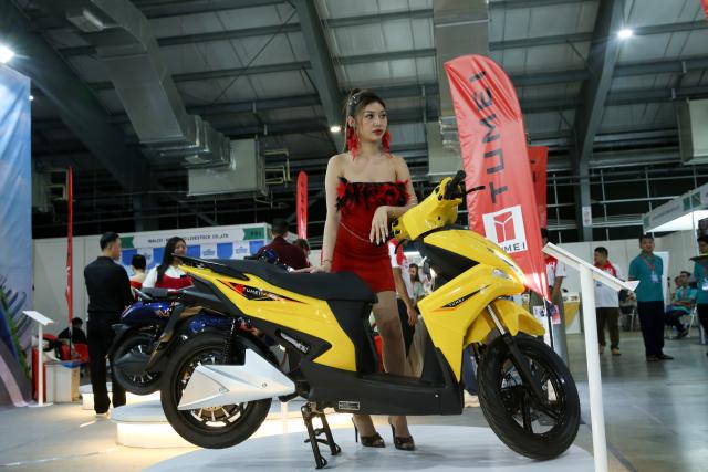 (251017) -- YANGON, Oct. 17, 2025 (Xinhua) -- A model poses beside an electric bike at an exhibition in Yangon, Myanmar, Oct. 17, 2025. TO GO WITH "Feature: China's electric two-wheelers gain popularity in Myanmar" (Xinhua/Myo Kyaw Soe)