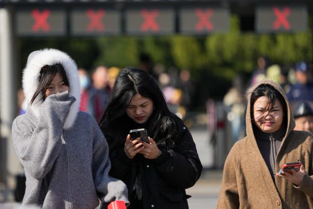 (251018) -- BEIJING, Oct. 18, 2025 (Xinhua) -- People walk against strong wind outside the east gate of the Temple of Heaven in Beijing, capital of China, Oct. 18, 2025. Affected by strong cold air, Beijing is hit by a cold wave. (Xinhua/Ju Huanzong)