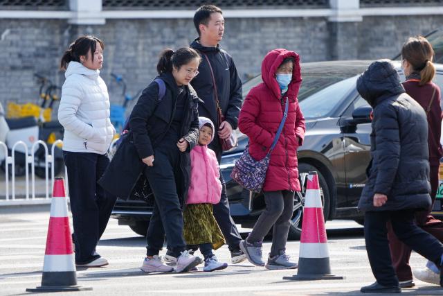 (251018) -- BEIJING, Oct. 18, 2025 (Xinhua) -- People wearing down jackets walk on a street in Beijing, capital of China, Oct. 18, 2025. Affected by strong cold air, Beijing is hit by a cold wave. (Xinhua/Ju Huanzong)