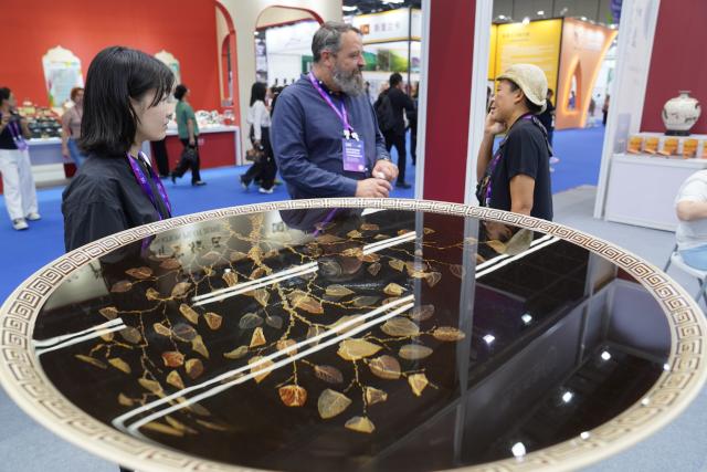 (251018) -- JINGDEZHEN, Oct. 18, 2025 (Xinhua) -- A foreign exhibitor (C) learns about a ceramic product during the 2025 China Jingdezhen International Ceramic Expo in Jingdezhen, east China's Jiangxi Province, Oct. 18, 2025. The 2025 China Jingdezhen International Ceramic Expo opened on Saturday in Jingdezhen, an eastern Chinese city famed as the "porcelain capital," attracting more than 1,000 buyers from home and abroad. (Xinhua/Zhou Mi)