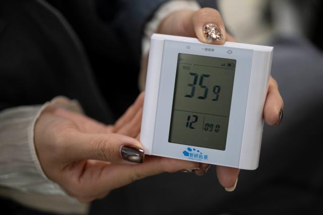 (251020) -- HARBIN, Oct. 20, 2025 (Xinhua) -- A resident displays a device with one-click repair report function in Harbin, northeast China's Heilongjiang Province, Oct. 20, 2025. Harbin, China's northernmost provincial capital, entered its heating season on Monday. Residents are now benefiting from improved heating services following an upgrade to the heating system. (Xinhua/Zhang Tao)
