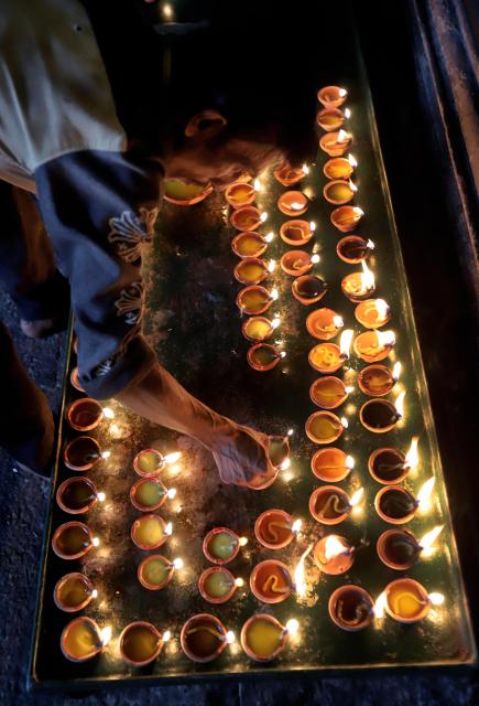 (251020) -- COLOMBO, Oct. 20, 2025 (Xinhua) -- A man lights oil lamps to celebrate Diwali, or the Hindu festival of lights, at a temple in Colombo, Sri Lanka, on Oct. 20, 2025. (Photo by Ajith Perera/Xinhua)