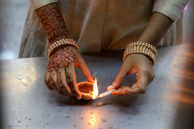 (251020) -- YANGON, Oct. 20, 2025 (Xinhua) -- A woman lights an oil lamp to celebrate Diwali, or the Hindu festival of lights, in Yangon, Myanmar, Oct. 20, 2025. (Xinhua/Myo Kyaw Soe)