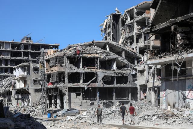 (251020) -- GAZA, Oct. 20, 2025 (Xinhua) -- People are seen on a street with destroyed buildings in Gaza City, on Oct. 19, 2025. The Israel Defense Forces (IDF) said in a statement on Sunday that it had launched a new wave of strikes against Hamas militant targets in the southern Gaza Strip.
   According to the statement, the strikes were led by the IDF's Southern Command "following a ceasefire violation earlier in the day." (Photo by Rizek Abdeljawad/Xinhua)