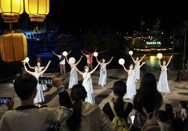 (251021) -- HEPU, Oct. 21, 2025 (Xinhua) -- Tourists watch a performance at a scenic area in Hepu County of Beihai City, south China's Guangxi Zhuang Autonomous Region, Oct. 20. 2025.
  As one of the starting ports of the historic Maritime Silk Road in ancient China's Han Dynasty (202 B.C.-220 A.D.), Hepu County in Guangxi has vigorously developed relevant cultural tourism. (Xinhua/Zhou Jiayi)
