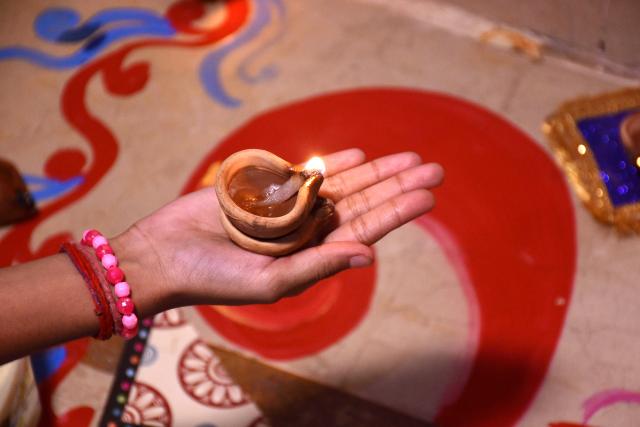 (251021) -- KARACHI(PAKISTAN), Oct. 21, 2025 (Xinhua) -- A woman holds an oil lamp to celebrate Diwali, or the festival of lights, in southern Pakistani port city of Karachi, Oct. 21, 2025. (Str/Xinhua)