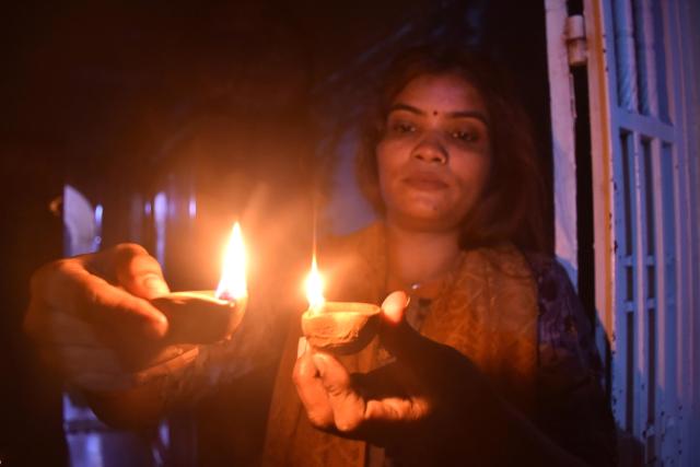 (251021) -- KARACHI(PAKISTAN), Oct. 21, 2025 (Xinhua) -- A woman lights oil lamps to celebrate Diwali, or the festival of lights, in southern Pakistani port city of Karachi, Oct. 21, 2025. (Str/Xinhua)