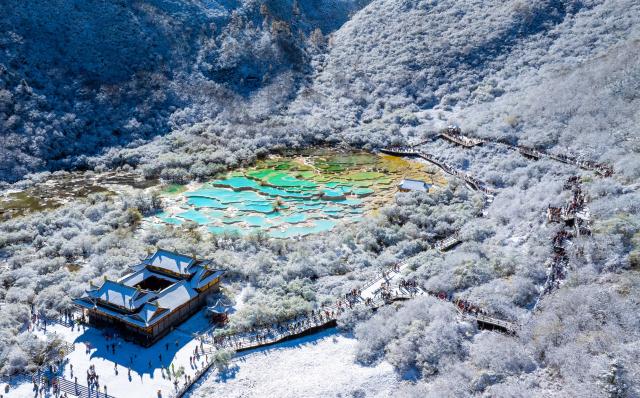 (251022) -- ABA, Oct. 22, 2025 (Xinhua) -- An aerial drone photo taken on Oct. 21, 2025 shows a view of a colorful pond cluster after snow at the Huanglong scenic area in Aba Tibetan and Qiang Autonomous Prefecture, southwest China's Sichuan Province.
  Huanglong witnessed the first snowfall of this autumn on Tuesday. (Photo by Sun Jiapeng/Xinhua)