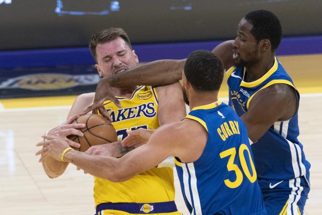 (251022) -- LOS ANGELES, Oct. 22, 2025 (Xinhua) -- Los Angeles Lakers' Luka Doncic (L) fights against Golden State Warriors' Jonathan Kuminga (R) and Stephen Curry during the 2025-2026 NBA regular season match between Los Angeles Lakers and Golden State Warriors in Los Angeles, the United States, Oct. 21, 2025. (Photo by Ringo Chiu/Xinhua)