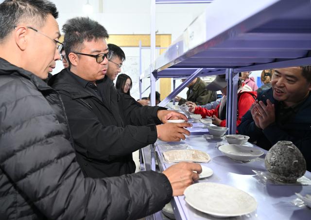 (251022) -- YINCHUAN, Oct. 22, 2025 (Xinhua) -- Chai Pingping (2nd L) introduces the progress in porcelain excavation to experts at the cultural relics storage room of the archaeologist team working on the remnants of the Suyukou kiln, in Yinchuan, capital of northwest China's Ningxia Hui Autonomous Region, Oct. 13, 2025. Remnants of the Suyukou kiln were discovered in 2017 in Yinchuan, capital of Ningxia, and cover an area of roughly 40,000 square meters.
   From 2021 to 2025, archaeologists from the Ningxia Institute of Cultural Relics and Archaeology and Fudan University found remnants of workshops featuring eight furnaces, as well as pits where workers used to mine porcelain clay, coal, quartz, lime and other raw materials and fuels, which were needed to make porcelain. 
   The Suyukou site is believed to be the earliest Western Xia Dynasty kiln site found to date in China. Judging from its production scale and saggars marked with the character guan, which literally means official, archaeologists believe that the Suyukou kiln was an official kiln producing bowls, cups, plates and other daily utensils -- mainly for the royal family during the Western Xia Dynasty (1038-1227). (Xinhua/Li He)