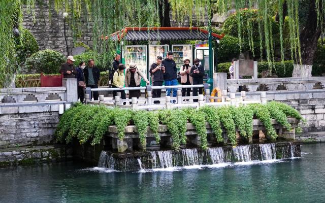 (251022) -- JINAN, Oct. 22, 2025 (Xinhua) -- People visit a spring along the spring greenway in Jinan, east China's Shandong Province, Oct. 22, 2025. Many citizens and tourists here have recently been attracted by spouting springs along the city's spring greenway, a 6.6-kilometer-long pavement connecting several springs and historical sites along the city's moat and Daming Lake Park. (Xinhua/Xu Suhui)
