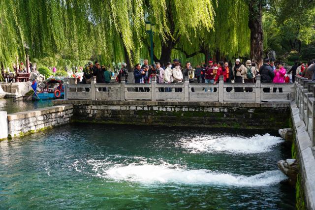 (251022) -- JINAN, Oct. 22, 2025 (Xinhua) -- People enjoy the spring scenery along the spring greenway in Jinan, east China's Shandong Province, Oct. 22, 2025. Many citizens and tourists here have recently been attracted by spouting springs along the city's spring greenway, a 6.6-kilometer-long pavement connecting several springs and historical sites along the city's moat and Daming Lake Park. (Xinhua/Xu Suhui)