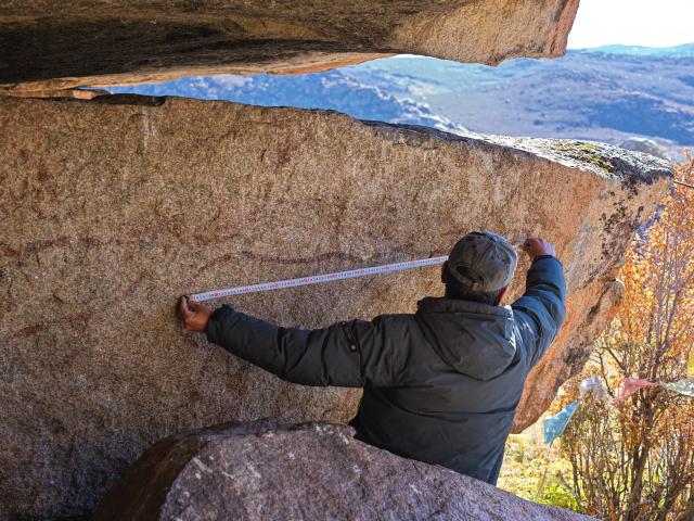 (251022) -- CHENGDU, Oct. 22, 2025 (Xinhua) -- Chen Xuesong, a cultural heritage conservator, measures a rock painting that features deer-shaped images in Garze Tibetan Autonomous Prefecture, southwest China's Sichuan Province, Oct. 21, 2025. This group of rock paintings in the prefecture dates back about 8,000 years. (Xinhua/Xue Chen)