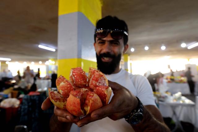 (251024) -- IRBID, Oct. 24, 2025 (Xinhua) -- A man shows a pomegranate during the 17th Annual Pomegranate and Rural Products Festival in Irbid, Jordan, Oct. 23, 2025. The festival kicked off here on Thursday. (Photo by Mohammad Abu Ghosh/Xinhua)
