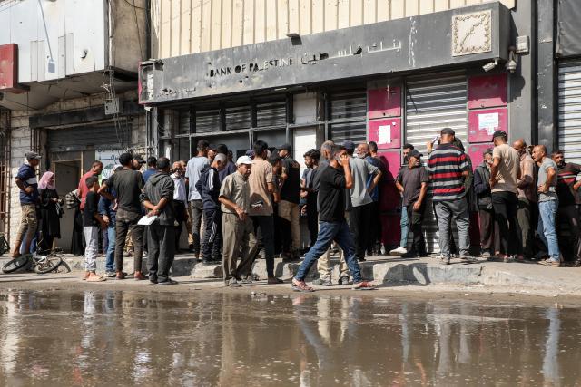 (251024) -- GAZA, Oct. 24, 2025 (Xinhua) -- Palestinians wait outside a branch of Bank of Palestine in Gaza City, on Oct. 23, 2025. Banks have reopened administratively but remain unable to bring cash into the Strip after two years of war. (Photo by Rizek Abdeljawad/Xinhua)