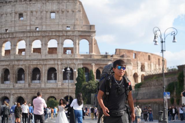 (251024) -- ROME, Oct. 24, 2025 (Xinhua) -- Chinese traveler on foot Cheng Long walks past the Colosseum in Rome, Italy, Oct. 19, 2025. TO GO WITH "Feature: From Xi'an to Rome on foot, one man's journey along the modern Silk Road" (Xinhua/Ren Yaoting)